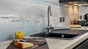 Una cucina moderna con un lavello in acciaio inossidabile, un tagliere, un peperone giallo e un coltello.