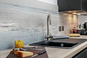 Una cocina moderna con un lavabo de acero inoxidable, tabla de cortar, un pimiento amarillo y un cuchillo.