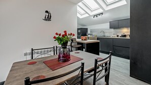 Una cucina moderna con lucernari, una zona pranzo con un vaso di rose rosse e un tema di arredamento in bianco e nero.