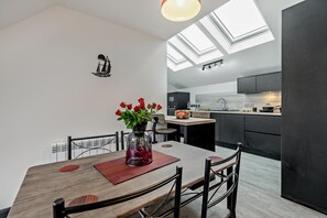 Una cocina moderna con tragaluces, un comedor con un jarrón de rosas rojas y una decoración en blanco y negro.