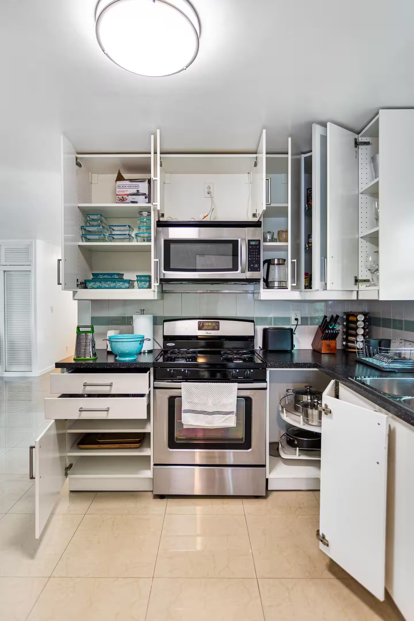 Une cuisine moderne avec des meubles blancs, une cuisinière en acier inoxydable, un four à micro-ondes et un grille-pain.