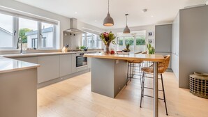 A modern kitchen with a central island, bar stools, pendant lighting, and a view of the outdoors. - 4 Bed in St. Merryn (oc-t29153) (Saint Merryn)