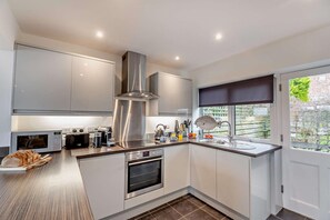 Una cocina moderna con electrodomésticos de acero inoxidable, horno empotrado y un amplio ventanal con vistas al exterior.