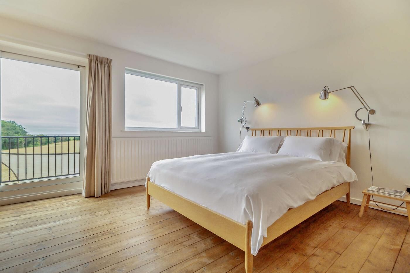 Une chambre à coucher avec un lit en bois, une grande fenêtre et une vue sur un court de tennis.