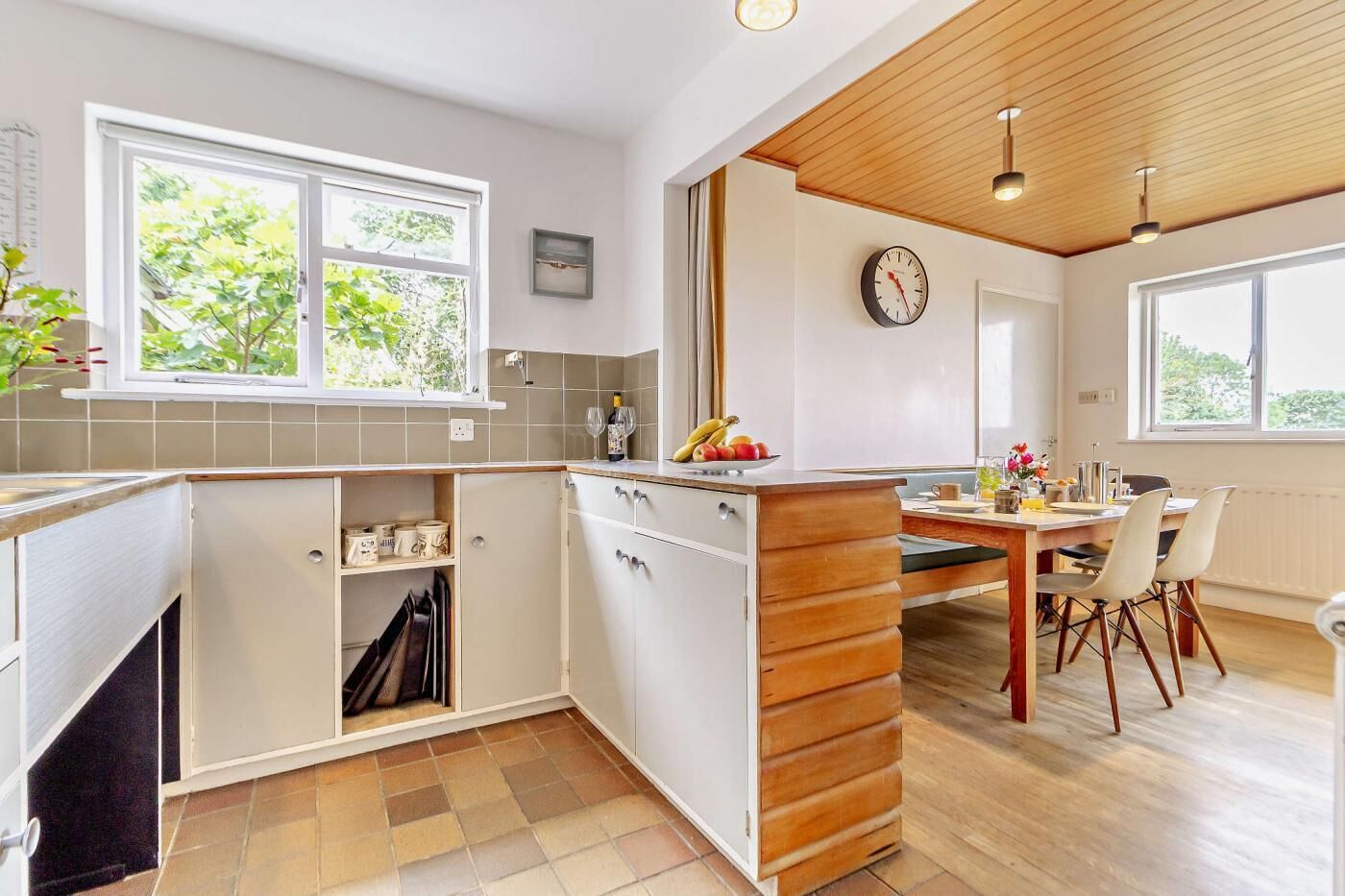 A modern kitchen with a wooden island, white cabinets, and a dining area with a table and chairs.
