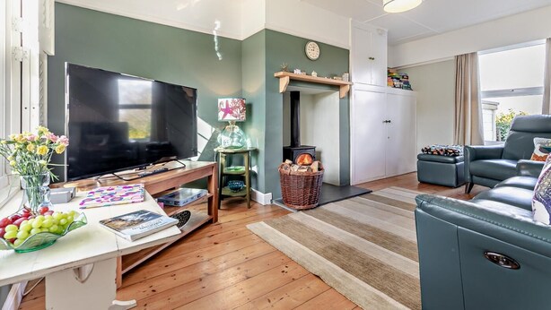 Een woonkamer met een televisie, een open haard, een bank en een eethoek met een tafel en stoelen.