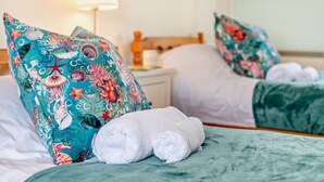 Een hotelkamer met twee bedden, elk voorzien van een kussen en een opgerolde handdoek.