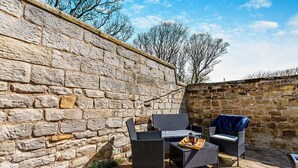An outdoor seating area with wicker furniture and a stone wall backdrop.