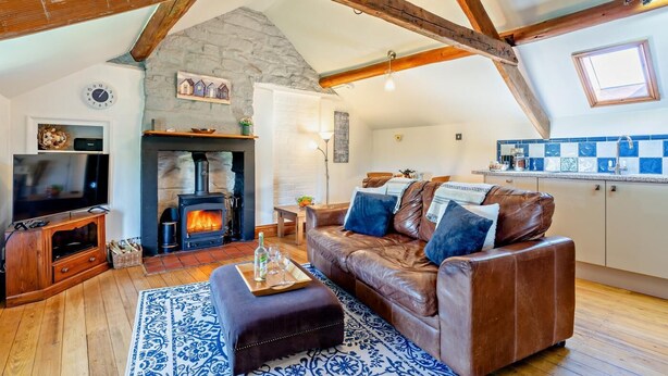 A cozy living room with a stone fireplace, a leather sofa, and a television.