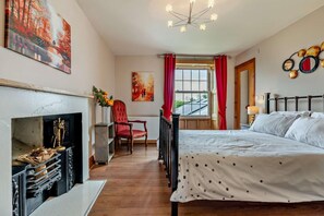 A bedroom with a bed, a fireplace, a chair, a window with curtains, and a painting on the wall. - 4 Bed in Port Mulgrave (oc-r29068) (Port Mulgrave)