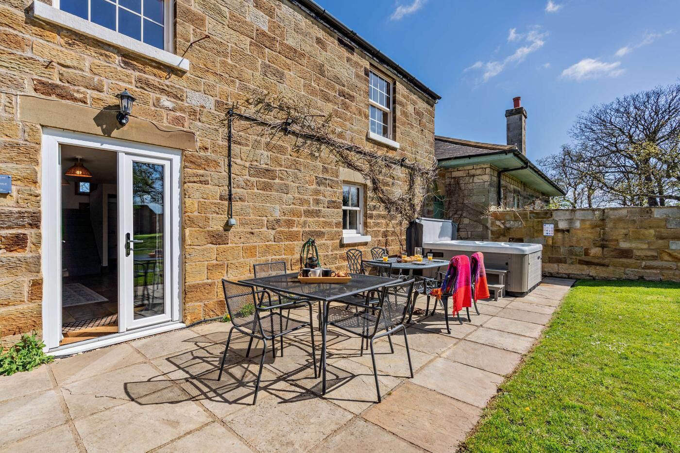 A stone building with a patio, outdoor seating, and a barbecue area.
