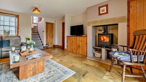 Ein gemütliches Wohnzimmer mit Kamin, einer Couch, einem Couchtisch und einem Fernseher.