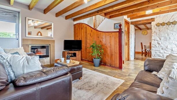 A cozy living room with a fireplace, leather sofas, wooden beams, a TV, and a stone wall. - 2 Bed in Port Mulgrave (oc-t29066) (Port Mulgrave)