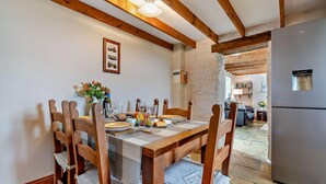 A dining area with a wooden table and chairs, a refrigerator, and a kitchen in the background. - 2 Bed in Port Mulgrave (oc-t29066) (Port Mulgrave)