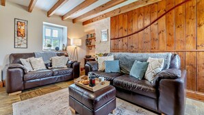 A cozy living room with two leather sofas, a wooden coffee table, and a large window. - 2 Bed in Port Mulgrave (oc-t29066) (Port Mulgrave)