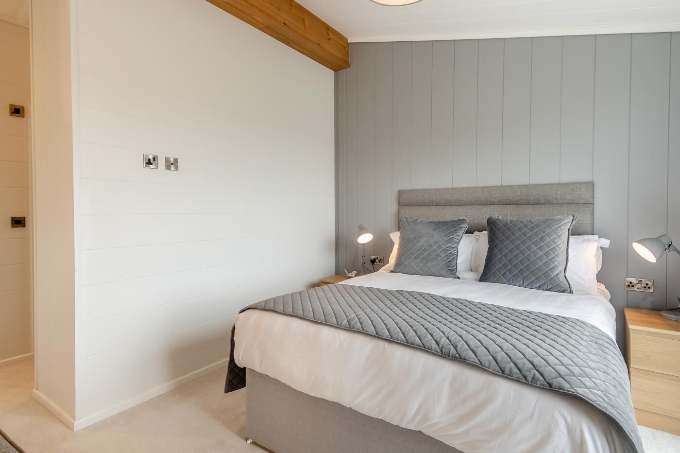 Une chambre à coucher avec un lit, des lampes de chevet et une poutre en bois au plafond.