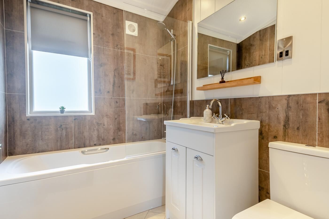 A modern bathroom with a bathtub, a vanity with a mirror, and a window.