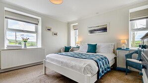 A bedroom with a bed, two bedside tables, a dresser, a radiator, and windows with blinds. - 3 Bed in Treknow (oc-h29194) (Treknow)
