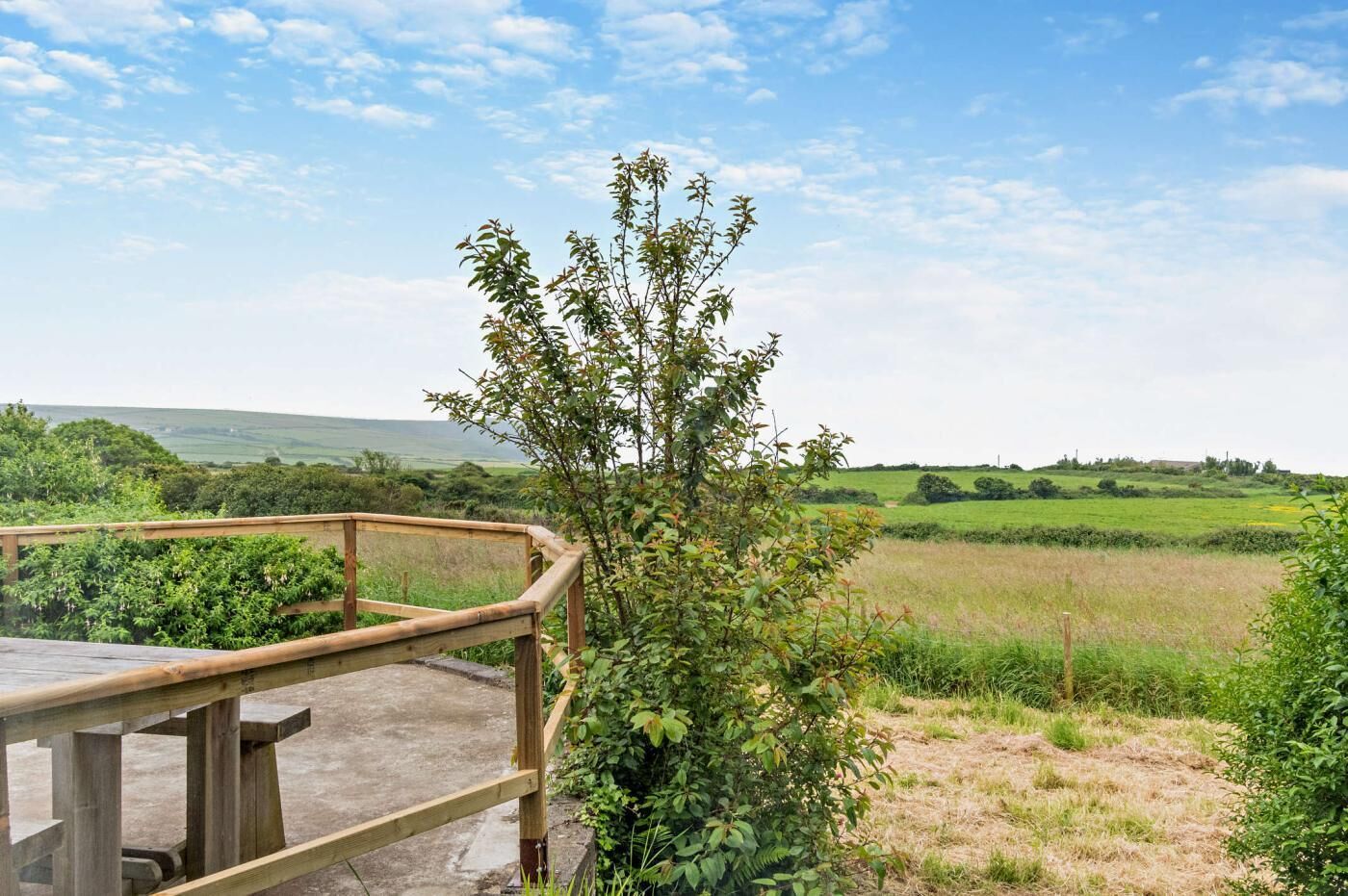 Una terraza de madera con vistas a un paisaje rural.