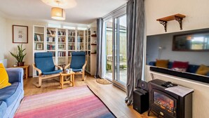 A cozy living room with a sofa, chairs, a bookshelf, a fireplace, and a TV. - 2 Bed in St. Dogmaels (oc-s29213) (Saint Dogmaels)