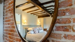A bedroom with a bed, a headboard, and a wall-mounted mirror reflecting the room. - 3 Bed in Weybourne (oc-t29167) (Weybourne)