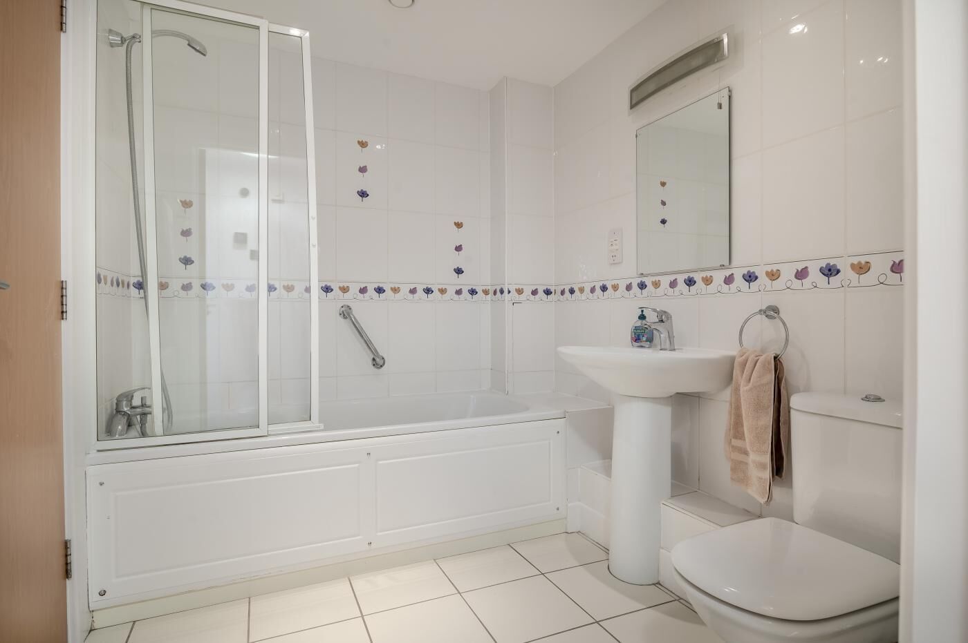 Une salle de bain avec une douche à parois de verre, un lavabo blanc et des toilettes.