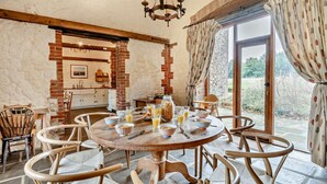 Zona pranzo rustica con un tavolo di legno rotondo, sedie in vimini e prodotti per la colazione.