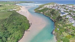 An aerial view of a coastal town with a beach, houses, and greenery.