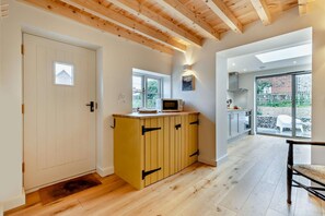 Een moderne keuken met houten kastjes, een magnetron en een raam.
