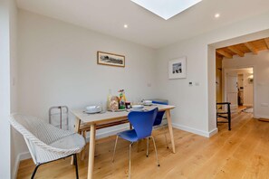 Un coin repas avec une table en bois, des chaises bleues et une chaise blanche avec un siège en osier tressé.
