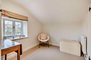Una habitación con ventana, una silla, una mesa y un radiador.