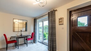 A room with a dining table, two chairs, a mirror, and a door with a window. - 1 Bed in Pluckley (oc-a29239) (Smarden)