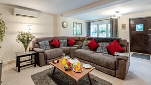 A living room with a sectional sofa, a coffee table with fruits and a glass of juice, a side table, and a plant. - 1 Bed in Pluckley (oc-a29239) (Smarden)