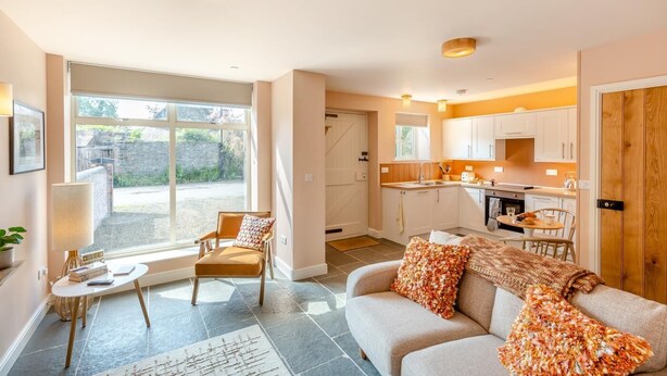 Una sala de estar acogedora con un sofá y un sillón, una mesita y vistas al exterior.