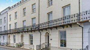 A row of white townhouses with black wrought iron balconies, each with a small door and windows. - 1 Bed in Tenby (oc-p29296) (Tenby)
