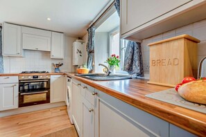 A modern kitchen with white cabinets, a wooden countertop, a built-in oven, and a breadboard. - 2 Bed in St. Issey (oc-t29235) (Saint Issey)