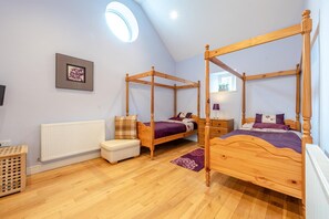 A bedroom with two four-poster beds, a radiator, a wooden chest of drawers, and a framed picture on the wall. - 3 Bed in Freshwater East (oc-w29240) (Freshwater East)