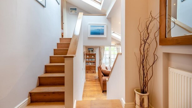 A staircase leading to a living area with a view of the sky, a bookshelf, and a plant. - 3 Bed in Freshwater East (oc-w29240) (Freshwater East)