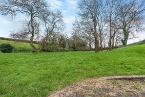 A grassy field with trees and a swing set. - 3 Bed in Freshwater East (oc-w29240) (Freshwater East)
