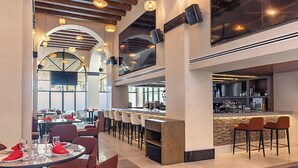 A modern restaurant with high ceilings, exposed beams, and a bar area with stools. - Cabo Beachfront condo for Holidays (Cabo San Lucas)
