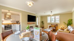 A modern living room with a dining area, a kitchen, and a TV mounted on the wall. - 2 Bed in Holt (oc-f29274) (Holt)