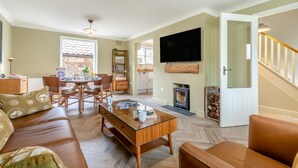 A spacious living room with a sofa, coffee table, and a television mounted on the wall. - 2 Bed in Holt (oc-f29274) (Holt)