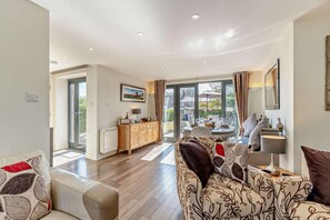 A modern living room with a sofa, a dining table, and a kitchen area with a cabinet.