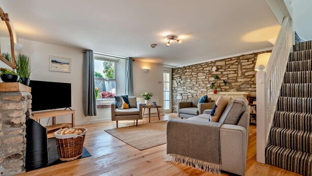 Ein geräumiges Wohnzimmer mit Steinwand, Kamin, Fernseher und Treppe.