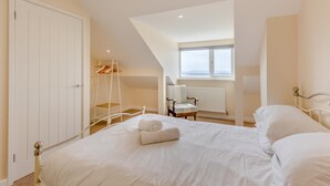 A bedroom with a large bed, a chair, a radiator, and a window. - 3 Bed in Aberdovey (oc-v29263) (Aberdovey)