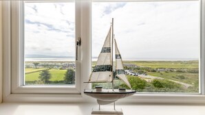 A model sailboat on a windowsill with a view of a coastal landscape. - 3 Bed in Aberdovey (oc-v29263) (Aberdovey)