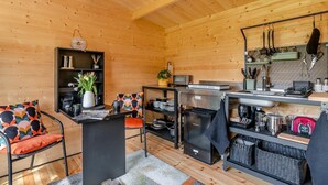 A wooden interior with a kitchen area, a dining table with chairs, and a small bookshelf. - 1 Bed in Cilycwm (oc-t29297) (Cilycwm)