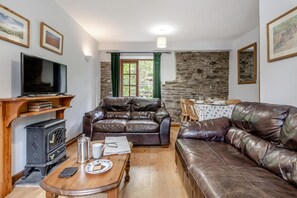 A living room with a stone wall, leather sofas, a wooden table, and a television. - 3 Bed in Knighton (oc-b29329) (Felindre)