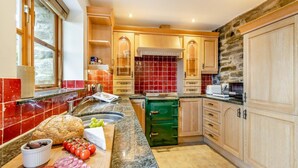 A kitchen with a marble countertop, wooden cabinets, and a stone wall. - 2 Bed in Knighton (oc-t29330) (Felindre)