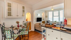 A dining area with a table, chairs, and a view into the living room. - 1 Bed in St. Ives (oc-l29205) (St Ives)